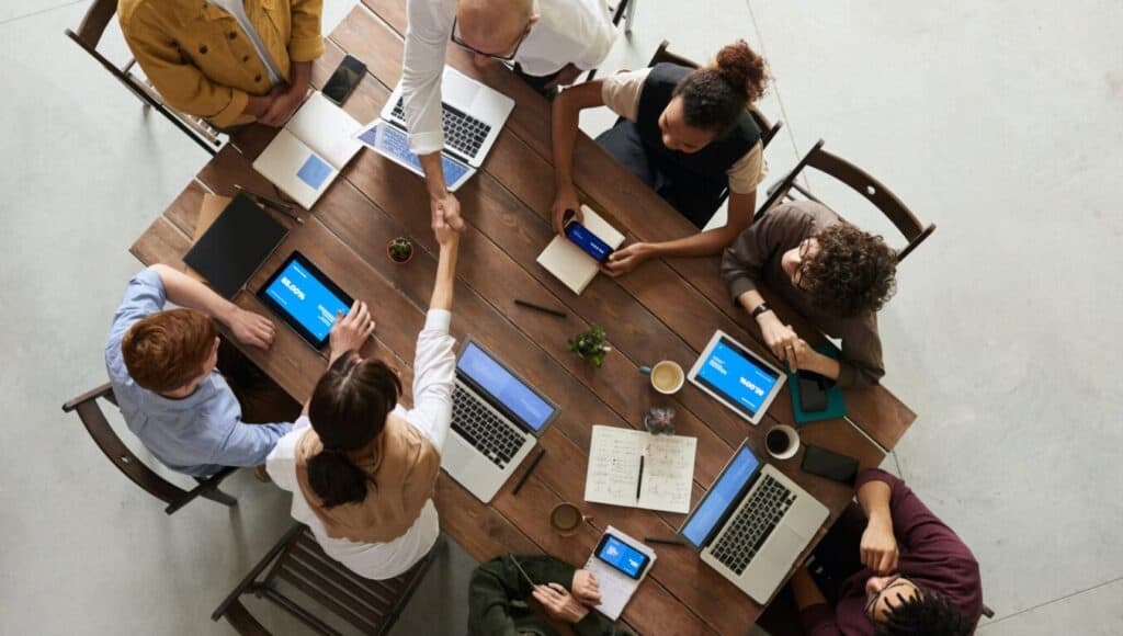 a group of people around a table with laptops