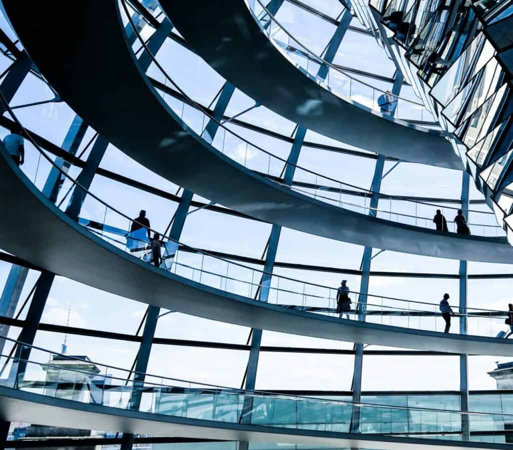 a group of people walking on a glass building with Reichstag building in the background